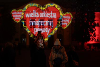 zdjęcie, czerwone serce z napisem wielka orkiestra świątecznej pomocy wyświetlana w nocy na elewacji budynku szkoły